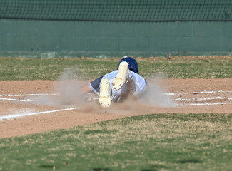 Action photo of athletic high school baseball player making an amazing play during a baseball game