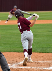 Action photo of athletic high school baseball player making an amazing play during a baseball game