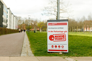 Schild im Park mit Hinweis zur Maskenpflicht