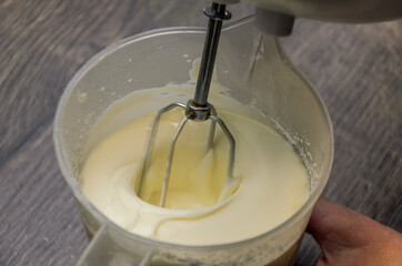 The chef whips the cake cream with an electric mixer	