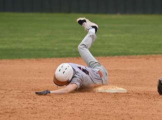 Action photo of athletic high school baseball player making an amazing play during a baseball game