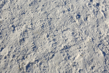 Many footprints in the snow on the pavement