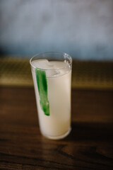 Highball gin cocktail with lychee, sparkling ginger water. Glass decorated with wasabi icing. 