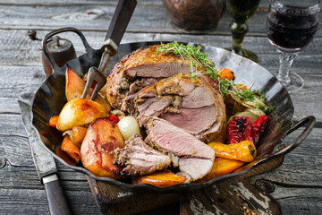 Traditional French leg of lamb with vegetable and fruits served as close-up in a rustic...