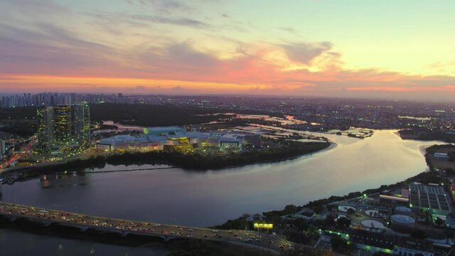 21 ZOOMED-OUT AERIAL IMAGE OF THE PINA NEIGHBORHOOD IN THE CITY OF RECIFE, PERNAMBUCO, BRAZIL, WITH THE SUN SETTING IN THE BACKGROUND AND THE CAPIBARIBE RIVER AND THE BRIDGE IN THE FOREGROUND