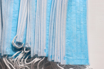 Stack of blue medical hygienic mask. Protective pandemic face masks on blue background. Pile of disposable surgical face mask against coronavirus, covid-19. Top view, copy space
