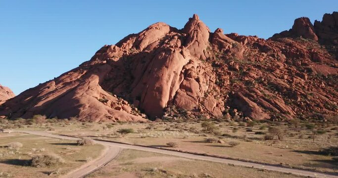 4K sunrise aerial footage of savanna, famous red granite Spitzkoppe Peak and Pontok Mountains in central Namibia between interior town Usakos and Atlantic west coast, southern Africa