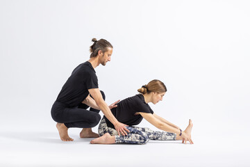 Fototapeta premium One Leg Folded Forward Bend Pose(Trianga Mukhaikapada).Yoga teacher correcting a student's posture.