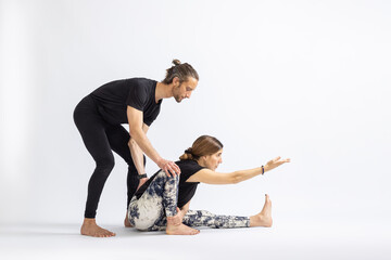 One Leg Folded Forward Bend Pose(Trianga Mukhaikapada).Yoga teacher correcting a student's posture.