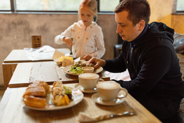 Family having breakfast in cafeteria at morning. Whole wheat waffles, ice cream, kiwi and coffee on brown wooden rustic table.