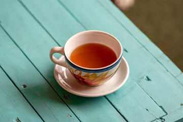 Té caliente en taza de flores sobre una mesa de madera azul