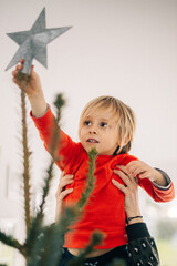 jeune enfant met l'&eacute;toile sur le sapin de no&euml;l