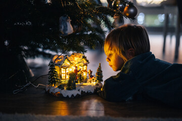 Jeune garçon regarde décoration de noël sous le sapin