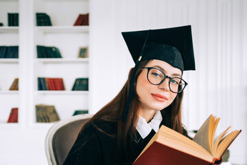 Portrait of confident young caucasian woman student with book in library, celebrating college...
