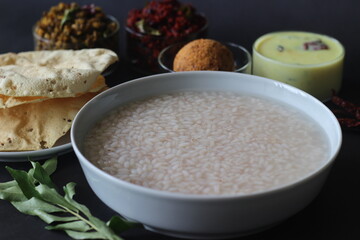 Fototapeta na wymiar Rice porridge or Kanji along with Coconut chutney, Beetroot potato thoran, stir fried moong, Fried papad and Tempered buttermilk