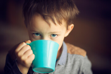 Chłopiec pije herbatę z kubka.