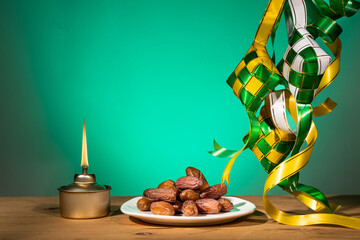 Muslim iftar of breaking of fast during Ramadan month with preserved sweet dates. Ketupat and pelita oil lamp as prop.