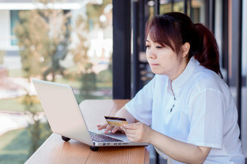 Online Payment . Asian woman holding credit card and using laptop with online shopping. Home shopping