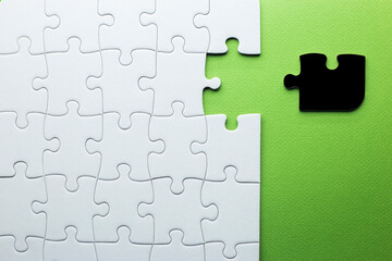 white puzzle with one piece missing to complete, but the missing piece is black and not the right...