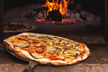 Foto op Plexiglas Taking a pizza out of a wooden oven with the fire burning in the background © Bruno