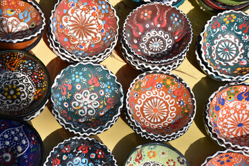 Fototapeta na wymiar Colorful and patterned touristic gift bowls made of ceramic in a Turkish bazaar. Traditional oriental and ottoman culture patterned bowls