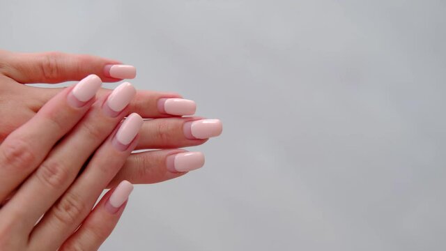 Female hands with old worn long lasting painted nails with pastel pink gel polish cover. Overgrown manicure. Time for correction gel polish. Nail care concept. Woman shows regrowth of her nails.