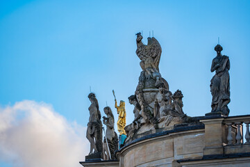 golden statue between stone sculptures on top of hu university of berlin