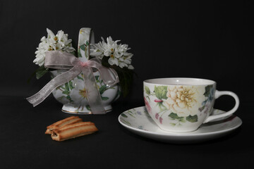 Snowdrops in a vase and tea with lemon, isolated on a black background