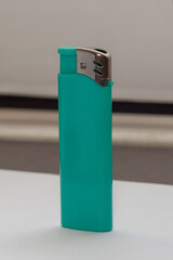 a turquoise gas lighter stands upright on the table