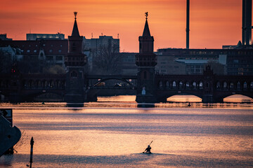 Fototapety  person paddling with canoe in spree to oberbaum bridge in berlin