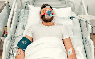 A sick man for coronavirus disease covid-19, who lies in the intensive care unit in a modern hospital with a ventilation mask.