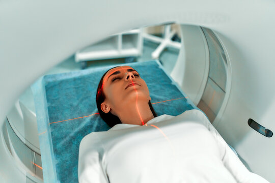 Portrait of a patient lying on CT or MRI, the bed moves inside the machine, scanning her body and brain. In a medical laboratory with high-tech equipment.