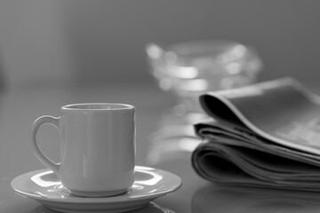 white cup on table with blurred newspaper behind