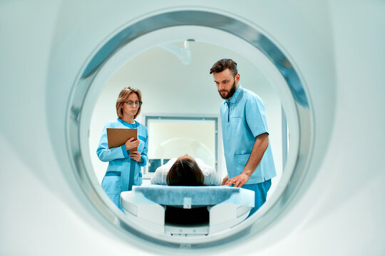 The patient lies on CT or MRI, the bed is moved inside the machine, scanning her body and brain under the supervision of a doctor and a radiologist. In a medical laboratory with high-tech equipment.