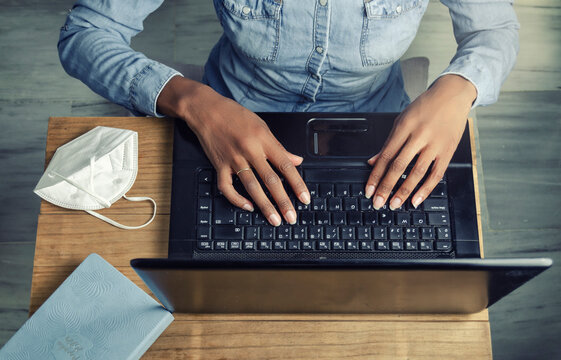 Top view of the hands of a black woman working or studying with a laptop. Covid-19 concept, new normal, home office