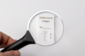 Close-up of a negative Covid-19 antigen test. a hand holds a magnifying glass over a negative Covid-19 antigen test. looking for a covid-19 test result.  