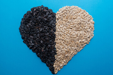A pile of watermelon seeds on a blue background in the shape of a heart