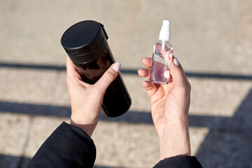 Naklejka premium hands hold alcohol antiseptic and mug of tea, prevent against infection of Covid-19 outbreak,woman washing hands with hand sanitizer to avoid contaminating with Corona virus