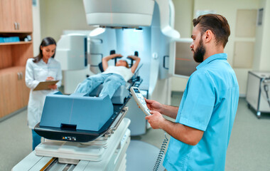 A young woman is undergoing radiation therapy for cancer under the supervision of doctors in a...