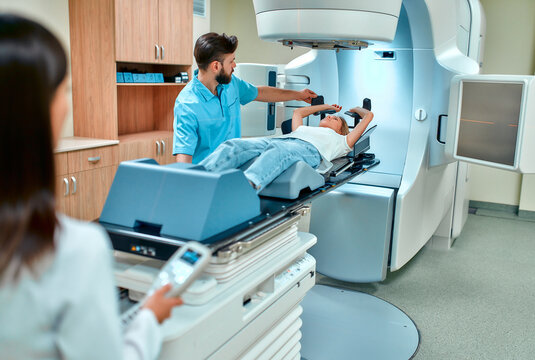 A young woman is undergoing radiation therapy for cancer under the supervision of doctors in a modern cancer hospital. Cancer therapy, advanced medical linear accelerator.