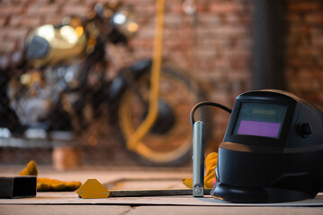 Welding helmet on the old motorcycle background in the garage.