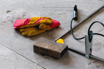 Welding gloves and metal frame on the floor background.