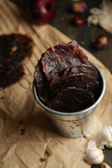 Homemade beef jerky seasoned with garlic, onion, pepper and salt. Jerky in a bucket on a wooden background