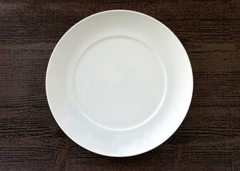 Empty White Plate against a Brown Wood Textured Background