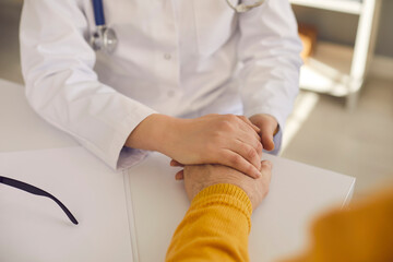 Cropped shot of doctor or nurse holding mature patient's hand soothing, comforting and reassuring him. Concept of trust, support, care, help, and health check for senior citizens