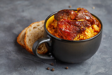 Pork pilaf with aromatic spices in a black bowl. Dishes of the national cuisine of the peoples of the East.