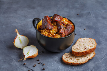 Pork pilaf with aromatic spices in a black bowl. Dishes of the national cuisine of the peoples of the East.