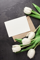 Greeting card with envelope, copy space and white tulip flowers on black background