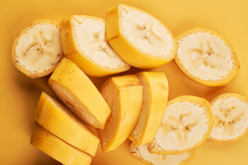 Sliced bananas on yellow background close up, healthy dessert ingredient