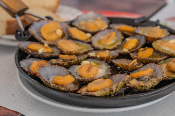 Seafood - grilled limpets served on a black plate. Lapas grelhadas.